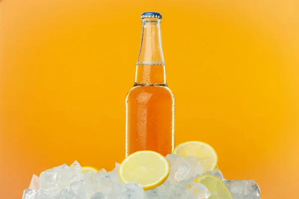Πάγος Λεμόνι Και Μπουκάλι Ποτό Πορτοκαλί Φόντο — Φωτογραφία Αρχείου