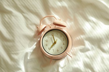 Sabahları yatağın üstünde pembe çalar saat.