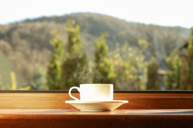 Bir fincan çay ahşap pencere eşiğinde duruyor.