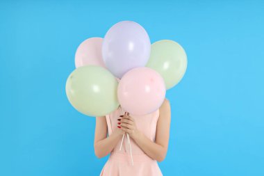 Mutlu yıllar, mavi arka planda balonları olan genç bayan.