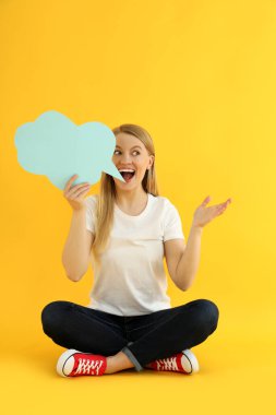 Sarı arka planda konuşma balonu olan genç bir kadın.