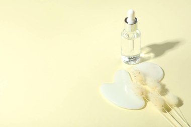 Yumuşak arkaplanda gua sha ve kozmetik içeren yüz bakımı kavramı