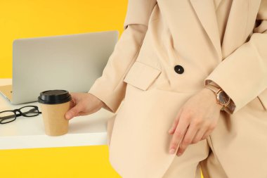 Genç iş kadını masada oturup kahve içiyor.