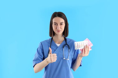 Mavi arka plan üzerinde çekici genç bir kadın doktor