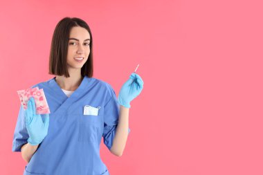 Pembe arka planda çekici genç bir bayan doktor.