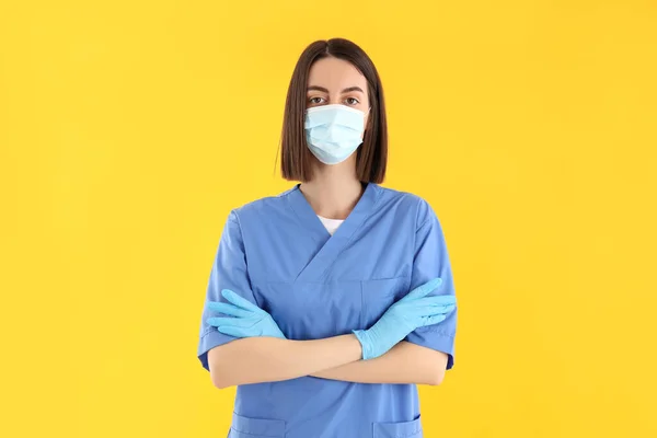 Attractive young female doctor on yellow background