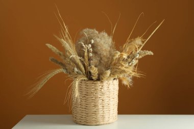 Kahverengi arka planda beyaz masada kurumuş çiçekler