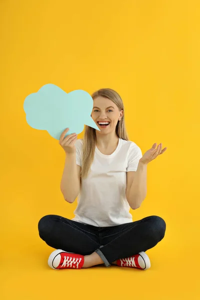 Young woman with speech bubble on yellow background