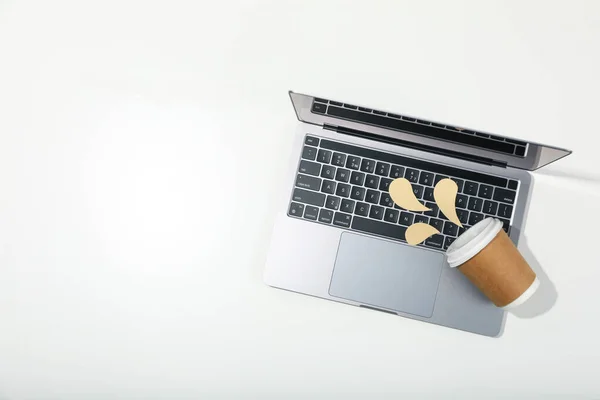 Concept of spilled drink, paper cup and decorative liquid on laptop