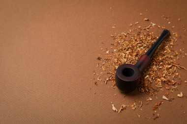 Kahverengi arka planda tütün olan sigara piposu.