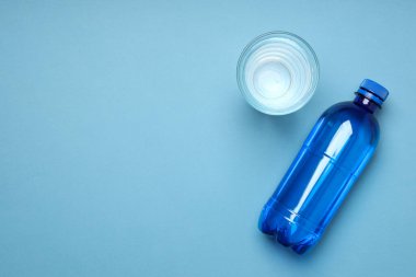 Bottle and glass of water on blue background