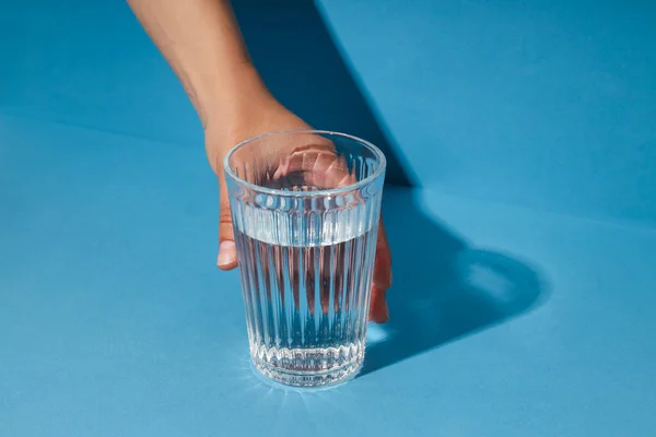 Female Hand Holding Glass Water Blue Background — Fotografia de Stock