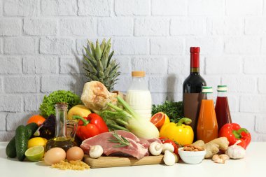 Group of different grocery on white table against brick wall background