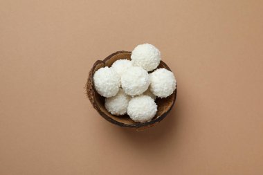Concept of tasty sweets on light brown background, coconut candies