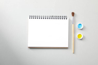 Blank notebook, brush and paints, top view