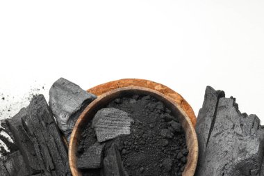 Natural hardwood charcoal and powdered charcoal on white background
