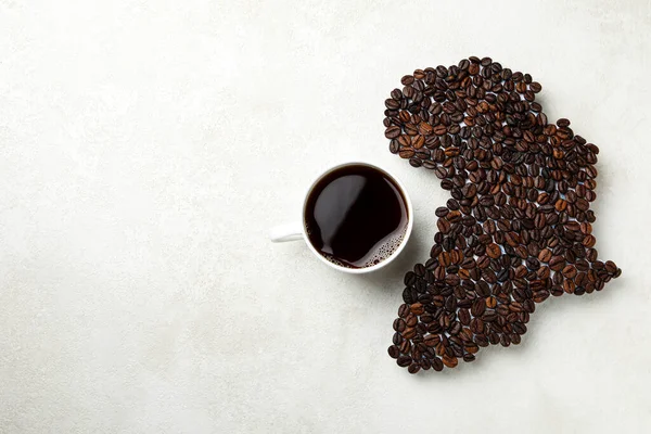 African continent made of coffee beans and cup of coffee on white textured background