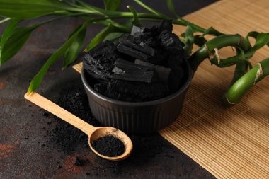 Bowl with charcoal and spoon with powdered charcoal, close up