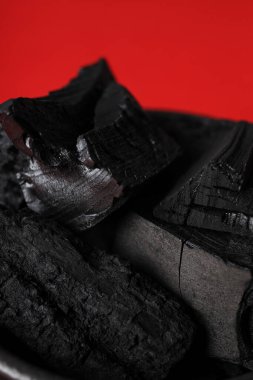 Natural hard wood charcoal on red background