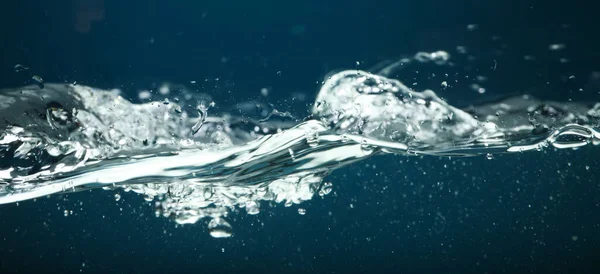 Water in aquarium against dark blue background, freshness concept