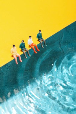 Yaz mevsimi kavramı, oyuncak insanlar suyun yanında oturur.