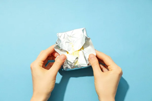 Female hands open package with butter on blue background