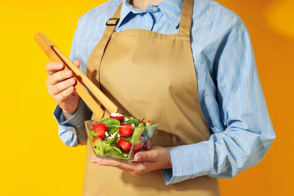 Woman Holds Salad Strawberry Wooden Tongs Yellow Background — 스톡 사진