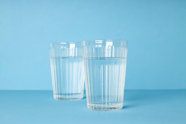 Two glasses of water on blue background