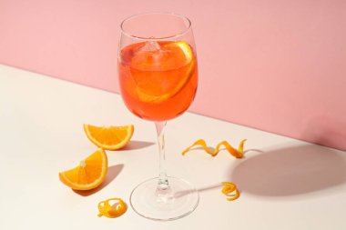 Concept of summer cocktail, Aperol Spritz on white table against pink background