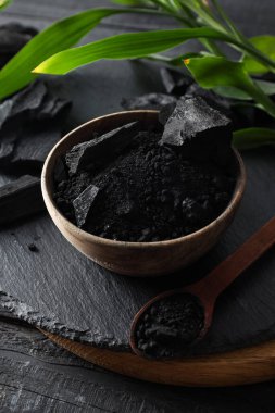 Natural charcoal and powdered charcoal on dark wooden background