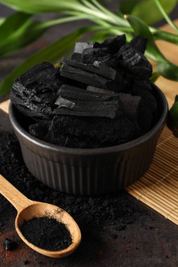 Bowl with charcoal and spoon with powdered charcoal, close up