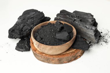 Natural hardwood charcoal and powdered charcoal on white background