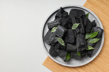 Tray with charcoal and leaves on bamboo mat
