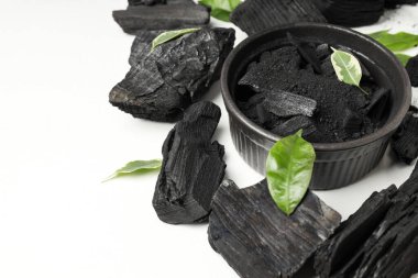 Charcoal, powdered charcoal and leaves on white background