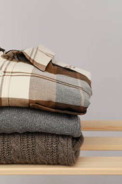 Wooden shelving with clothes against light background