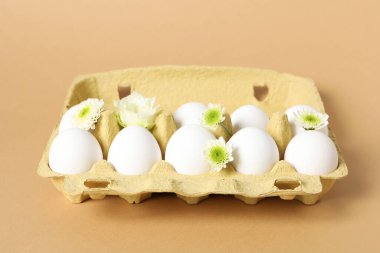 Concept of spring, eggs with flowers on beige background