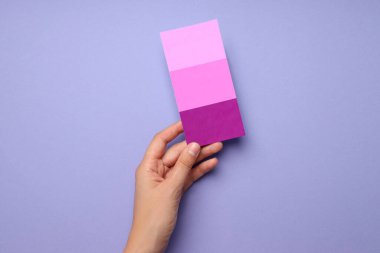 Menekşe arkaplanda renk paleti tutan kadın eli