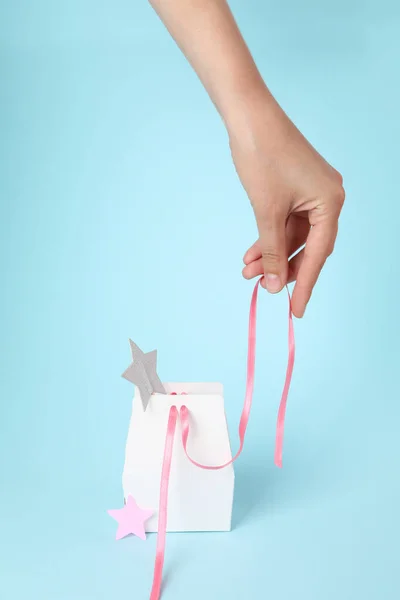 Concept of gift, female hand and gift bag on blue background
