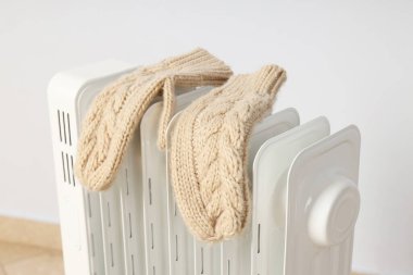Concept of heating season, modern electric heater with mittens