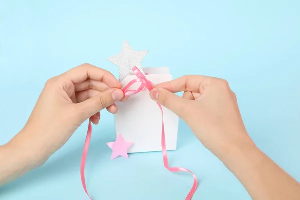 Concept of gift, female hands and gift bag on blue background