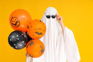 Cadılar Bayramı kavramı, sarı arka planda Cadılar Bayramı balonları olan Hayalet.