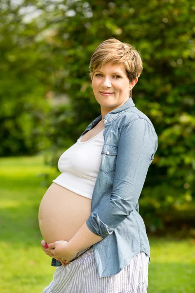 Zwangere vrouw op het gras — Stockfoto