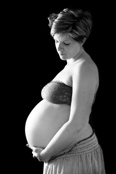 Беременный живот на черном фоне — стоковое фото