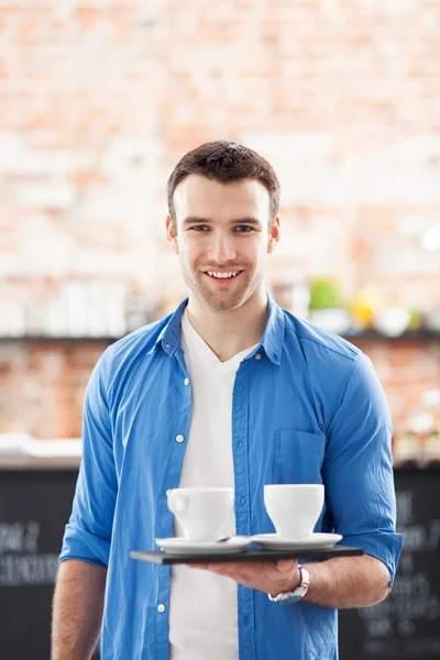 Garçom segurando copos de café no café — Fotografia de Stock