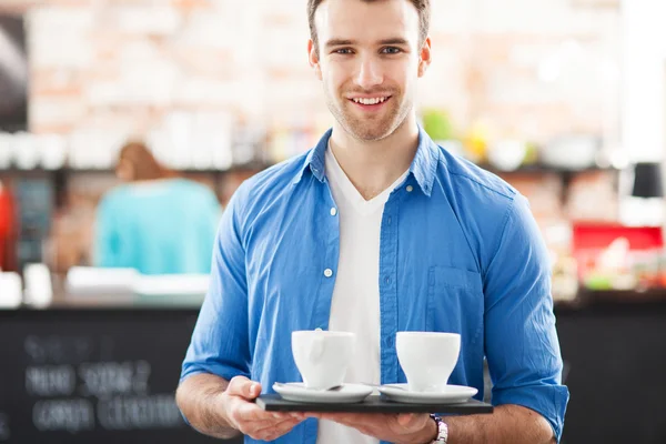 Číšník drží šálků kávy v kavárně — Stock fotografie