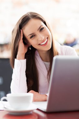 Kafede dizüstü bilgisayar kullanan genç bir kadın
