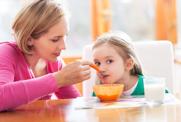 Mutter füttert ihre Tochter mit dem Löffel — Stockfoto