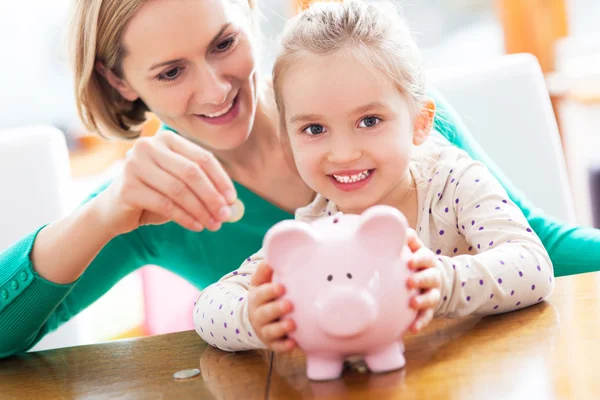 Moeder en dochter met piggy bank Rechtenvrije Stockafbeeldingen