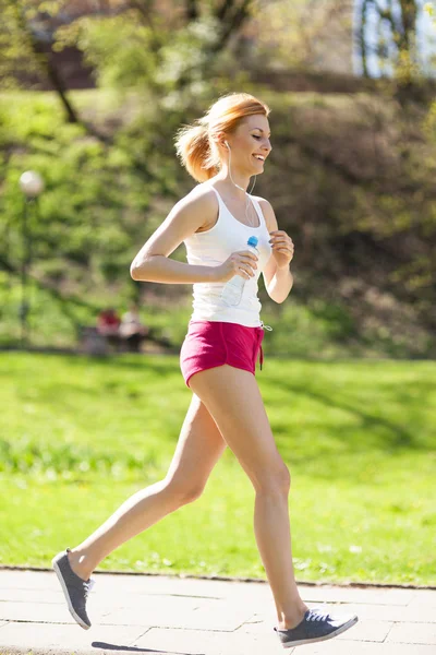Ung kvinna joggar i parken — Stockfoto