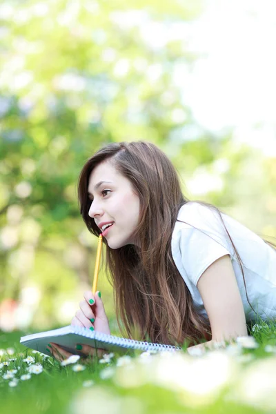 Chica acostada en la hierba con libro de trabajo —  Fotos de Stock
